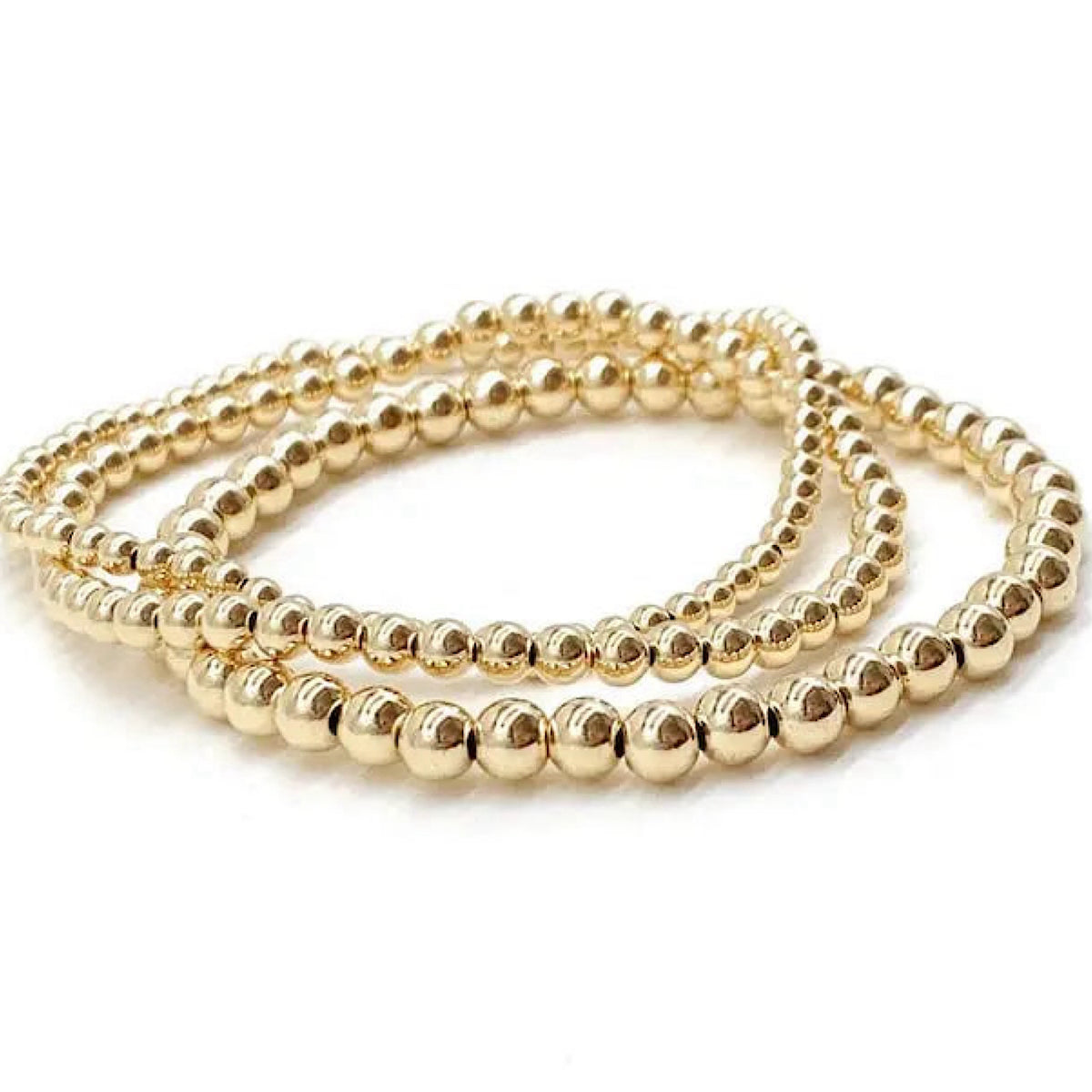 Three gold beaded stretch bracelets coiled together on a white background.