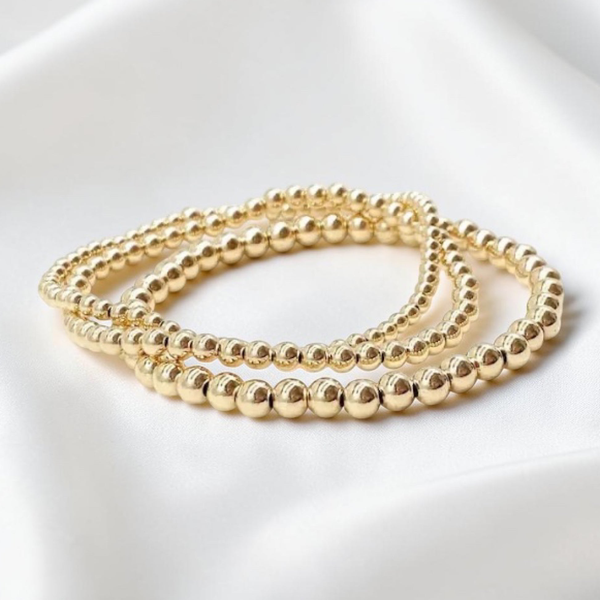 Three 14k gold filled beaded bracelets on a white background
