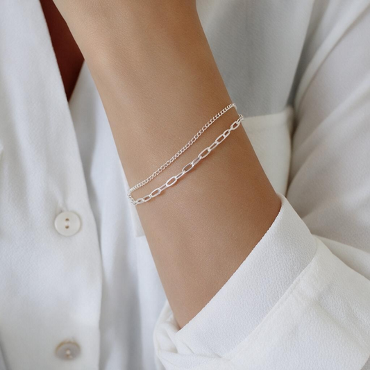Sterling silver double-chain bracelet worn on wrist” for a wrist shot, and “Close-up of two delicate sterling silver chains” for a detail shot.