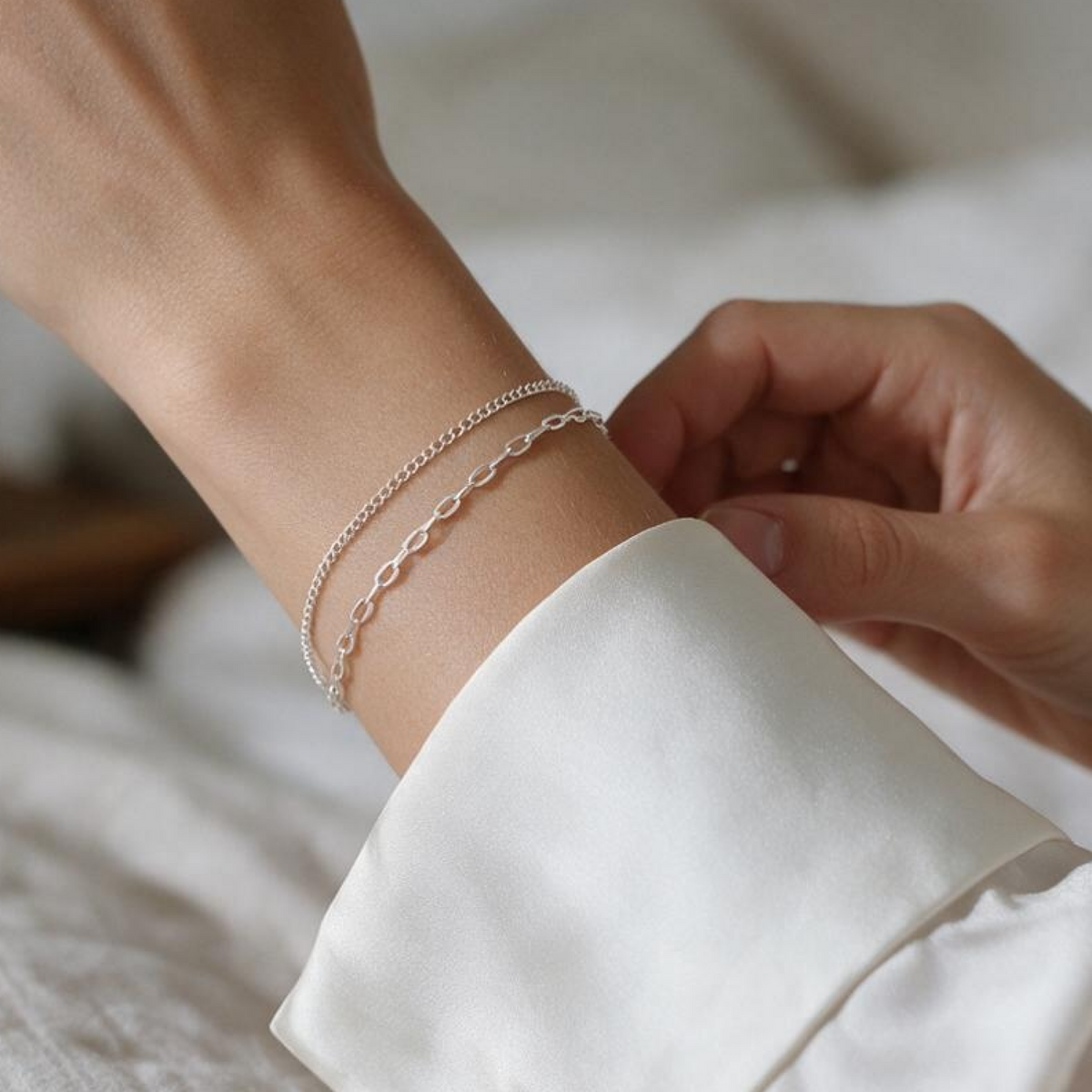 Sterling silver double-chain bracelet worn on wrist” for a wrist shot, and “Close-up of two delicate sterling silver chains” for a detail shot.