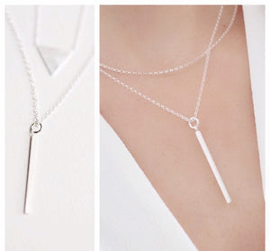 This fashionable silver necklace features a thin vertical bar pendant with a sleek minimalist look. It's the perfect accessory for an up-to-date outfit.

